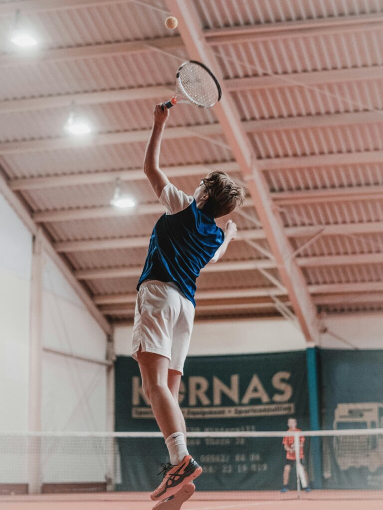 A tennis player jumps to hit the ball during an intense indoor match.